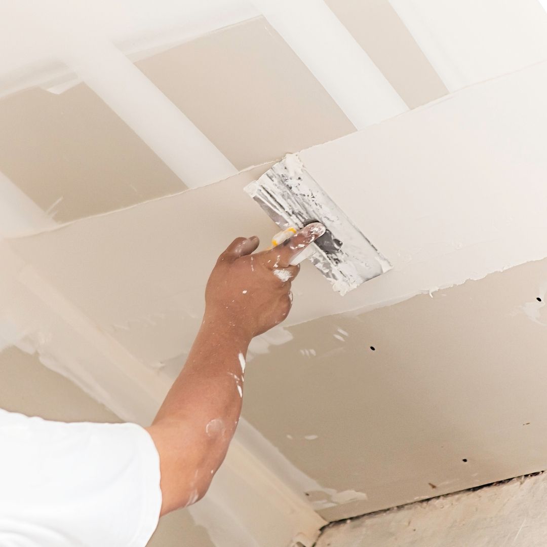 Plasterer patching and finishing a ceiling