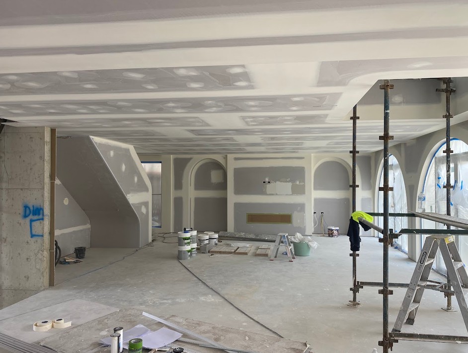 Two tradesmen lifting a sheet of plasterboard